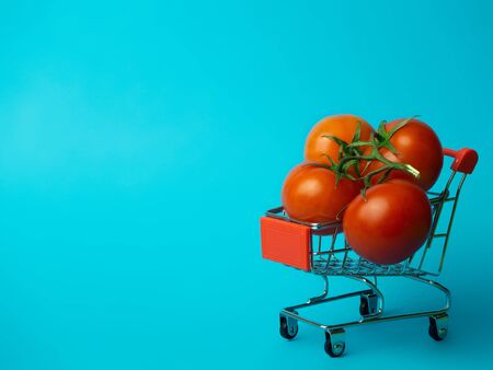 Small trolley with tomatoes on a blue background.の写真素材