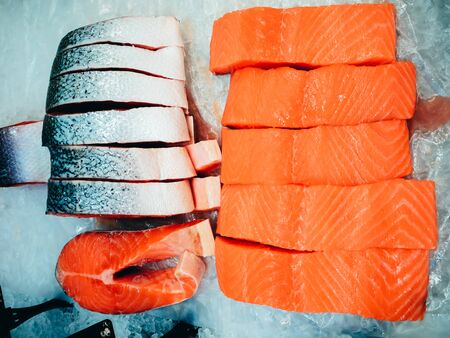 Salmon fillet and steaks lay in ice in a store.