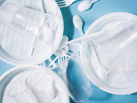 Plastic dishes, disposable tableware, plates, glasses, spoons, forks on a blue background. Caring for the environment. The problem is recycling. Reuse, safe planet, environmental concept. Trash.の写真素材