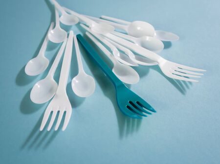 Plastic dishes, disposable tableware, plates, glasses, spoons, forks on a blue background. Caring...