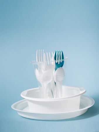 Plastic dishes, disposable tableware, plates, glasses, spoons, forks on a blue background. Caring for the environment. The problem is recycling. Reuse, safe planet, environmental concept. Trash.の写真素材