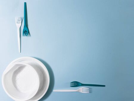 Plastic dishes, disposable tableware, plates, glasses, spoons, forks on a blue background. Caring...