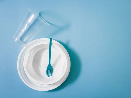 Plastic dishes, disposable tableware, plates, glasses, spoons, forks on a blue background. Caring for the environment. The problem is recycling. Reuse, safe planet, environmental concept. Trash.の写真素材