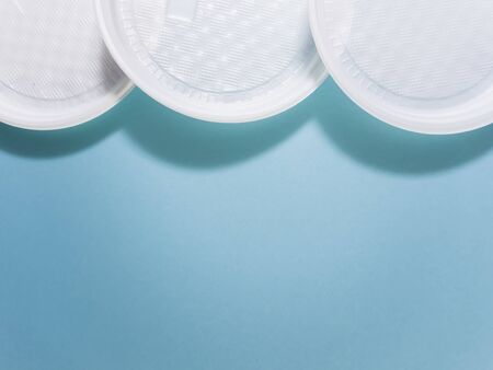 Plastic dishes, disposable tableware, plates, glasses, spoons, forks on a blue background. Caring for the environment. The problem is recycling. Reuse, safe planet, environmental concept. Trash.の写真素材