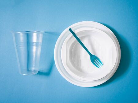 Plastic dishes, disposable tableware, plates, glasses, spoons, forks on a blue background. Caring for the environment. The problem is recycling. Reuse, safe planet, environmental concept. Trash.の写真素材