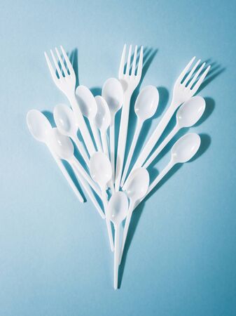 Plastic dishes, disposable tableware, plates, glasses, spoons, forks on a blue background. Caring for the environment. The problem is recycling. Reuse, safe planet, environmental concept. Trash.の写真素材