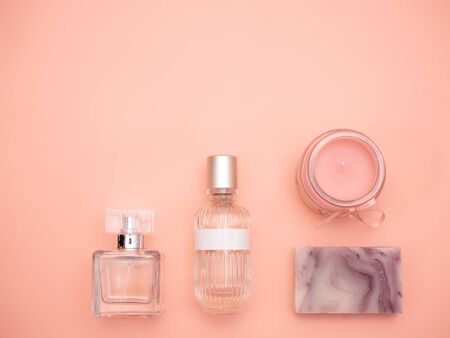 Bottle of perfume, scented candle and handmade soap isolated on a pink background. Flatlayの写真素材