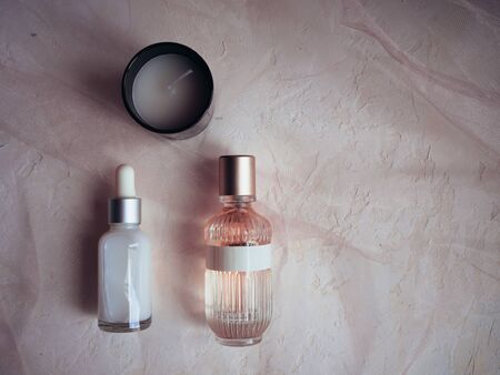 Bottle with perfume and cream on a pink background with aromatic candles.の写真素材