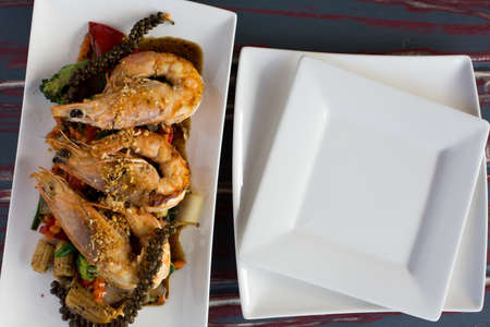 Top view of Grilled king prawns with fresh chilli and garlic relish and empty platesの写真素材