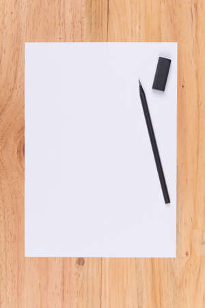 Top view of white paper, pencil and eraser on wooden table