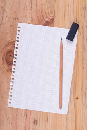 Top view of grid notepad,  pencil and eraser on wooden tableの写真素材