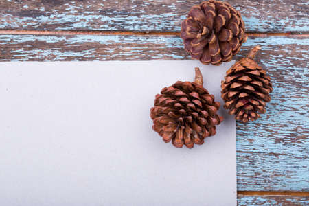Empty paper on blue wood texture with pine cones decoration background
