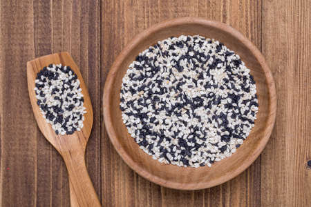 Top view of Mixed Sesame (Black Sesame and White Sesame) in wooden spoon on wooden background