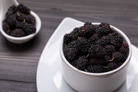 Fresh Black Mulberries in ceramic bowl on dark wooden background, selective focusの写真素材