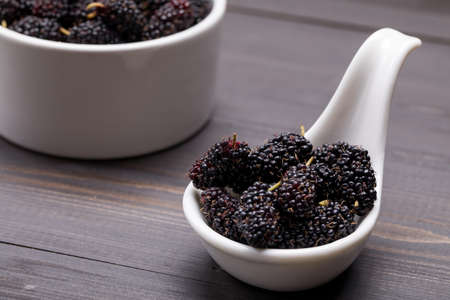 Fresh Black Mulberries in ceramic bowl on dark wooden background, selective focusの写真素材