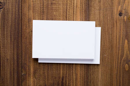 Top view of stack white business cards on dark wooden background, use for mock up branding identity