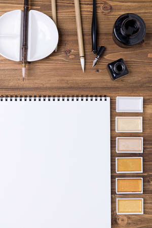 Top view of Calligraphy mediums (pen, ink, brush, paint) on wooden backgroundの写真素材