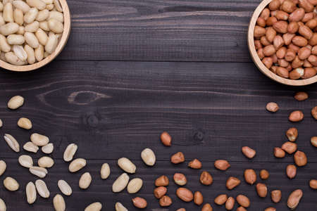 Dried Peanuts and Peeled Peanuts on dark wooden table, food backgroundの写真素材