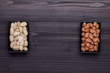 Dried Peanuts and Peeled Peanuts on dark wooden table, food backgroundの写真素材