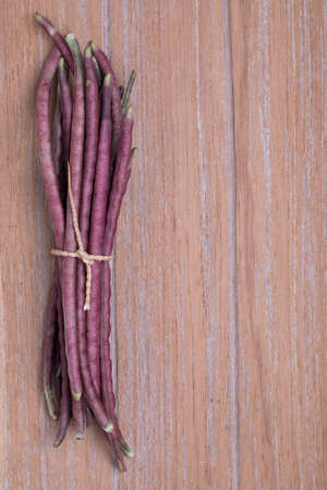 Purple Cowpea (Purple Yardlong Bean) on wooden background, top view with copy space
