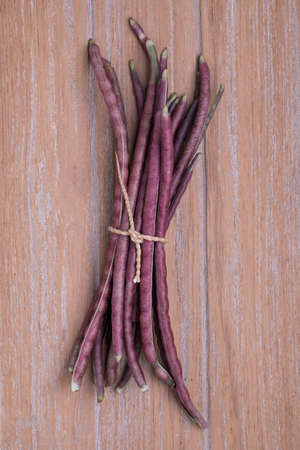 Purple Cowpea (Purple Yardlong Bean) on wooden background, top view
