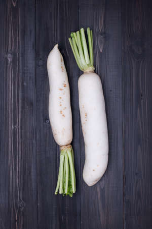 White Radish on dark wooden background, top view