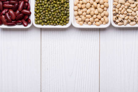 Assortment of Beans, Red kidney bean, Mung bean, Soy bean, and Navy bean on white wooden textured table, food background with copy spaceの写真素材
