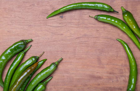 Large green chili (chili spur pepper) on wooden background, top viewの写真素材
