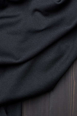 Creased black fabric texture on wooden background with copy spaceの写真素材