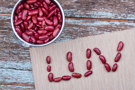 a word 'LUV' created by red beans on wood backgroundの写真素材