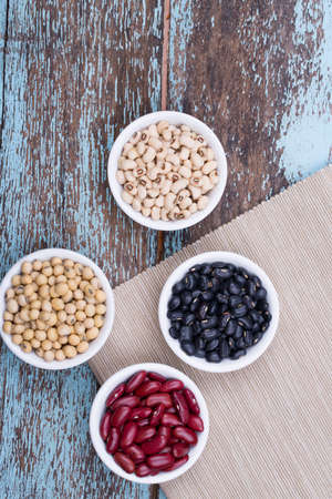 Soy beans, Red beans, black beans, and navy bean on blue wooden background