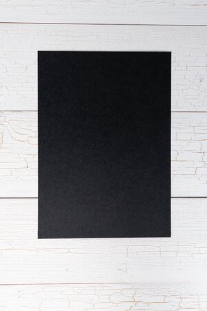 Blank black paper on white wooden background, copy space, templateの写真素材