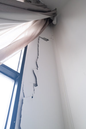 Broken window with white curtains on a white wall in a room from Earthquake in Condominium, Bangkok Thailandの写真素材