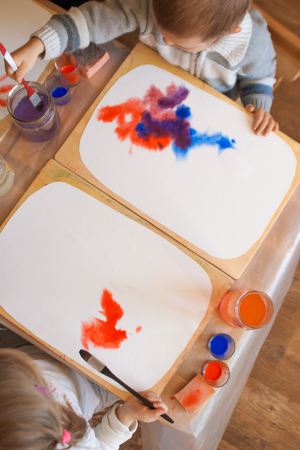 Close-up of watercolor wet-on-wet paints with small kids hand holding paintbrush and drawing in Waldorf kindergartenの写真素材