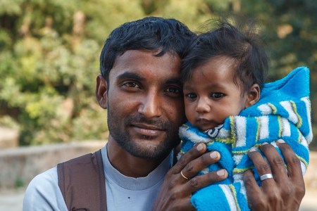 AGRA, INDIA - DECEMBER 2012: Indian family, father holding the daughter with black eyes in his lapのeditorial素材