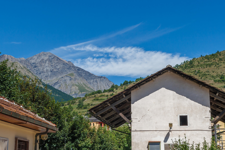Travelling in Italian Alps - Little alpine town house Highly in mountains at hot shiny summer morning with blue cloudy skyの写真素材
