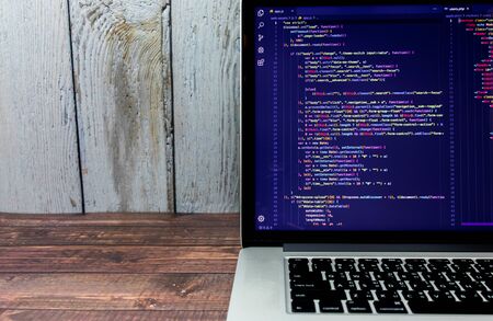The screen of the program source code on the laptop placed on the desk, which the programmer has developed into a website or mobile app, as system analysis and designer designedの写真素材