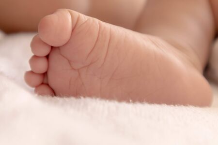 The feet of a newborn baby at a few months old Who is sleeping comfortably on the white mattress...