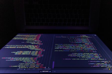 The shooting angle of the screen of the laptop program on the dark table, which the programmer developed into a website or mobile app. By system analysts and designersの写真素材