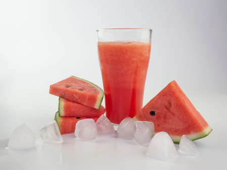 Watermelon smoothie with watermelon slices and ice cube on white backgroundの写真素材