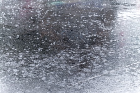 close up rain water drop falling in city street floor with the water