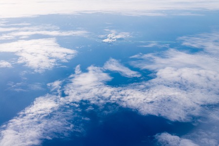 view from the window of an airplane flying in the clouds, top view of Blue ocean and white clouds from an airplane windowの写真素材