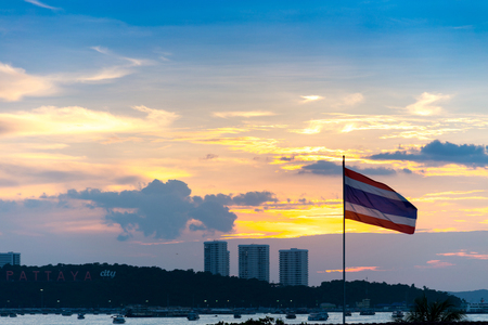 sunset sky with Pattaya city sign on hill at (Bali Hai Pier) Pattaya bay with speed boat and thailand flag. Chonburi,Thailandの写真素材