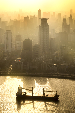 Smog lies over the skyline of Historical architecture and modern skyscraper on the bund of Shanghai city in misty gold lighting sunrise, Shanghai, China vintage picture styleの写真素材
