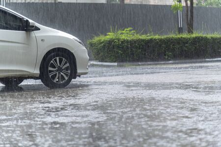 close up raindrops / water drop flooding on street floor in parking car.の写真素材