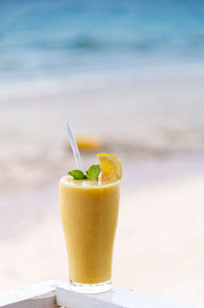 Fresh mango smoothie in glass on wood with outdoor backgroundの写真素材