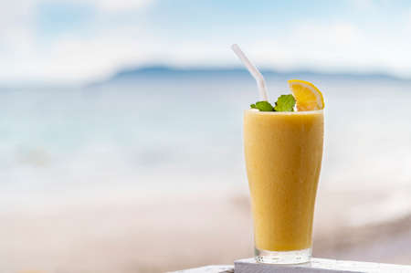 Fresh mango smoothie in glass on wood with outdoor backgroundの写真素材
