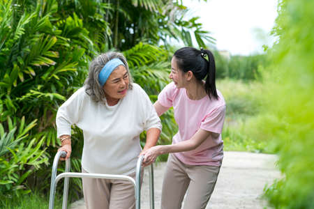 Happy Asian senior woman walking by walker, she living with Asian female physical therapist (nurse) take care.の写真素材