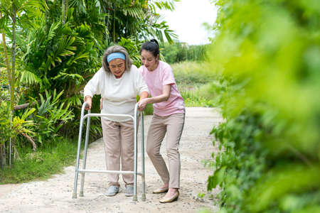 Happy Asian senior woman walking by walker, she living with Asian female physical therapist (nurse) take care.の写真素材