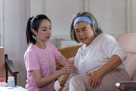 Asian young woman take care and  support older mother sick in living room. family conceptの写真素材